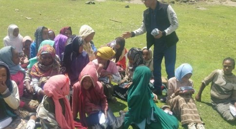 Distributing pads to girls seated on the grass